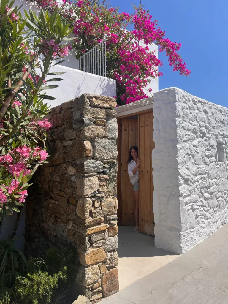 a woman opening the door of a typical Greek house in Mykonos