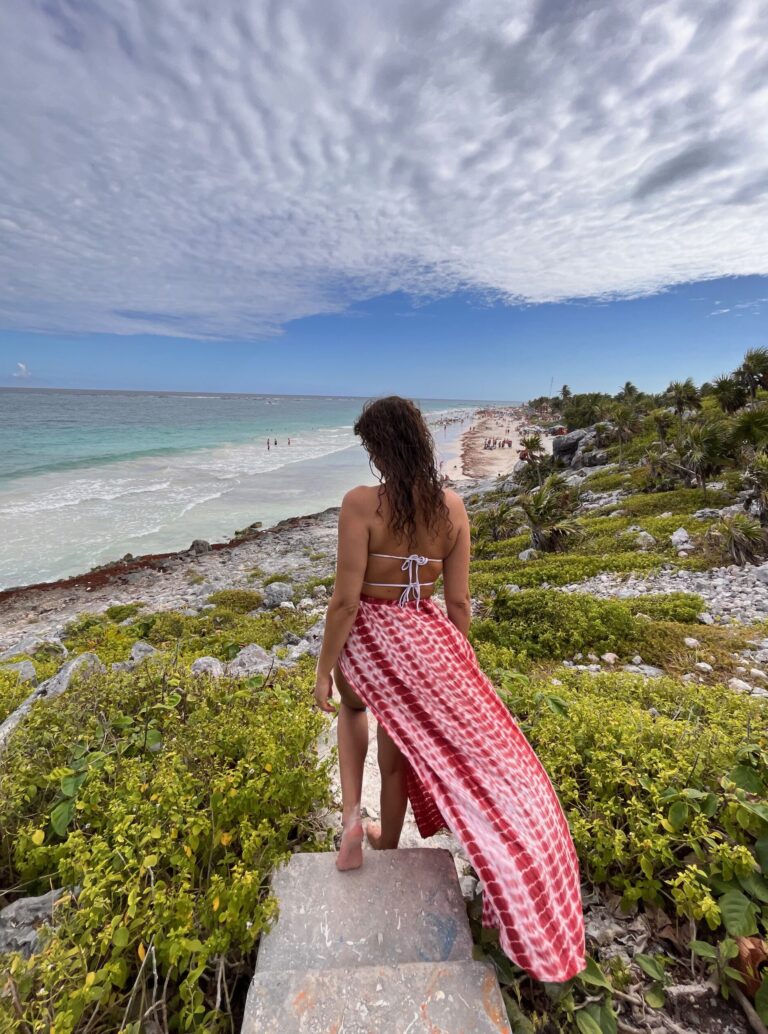 a woman overlooking the beach of Tulum from the standpoint of the Mayan ruins