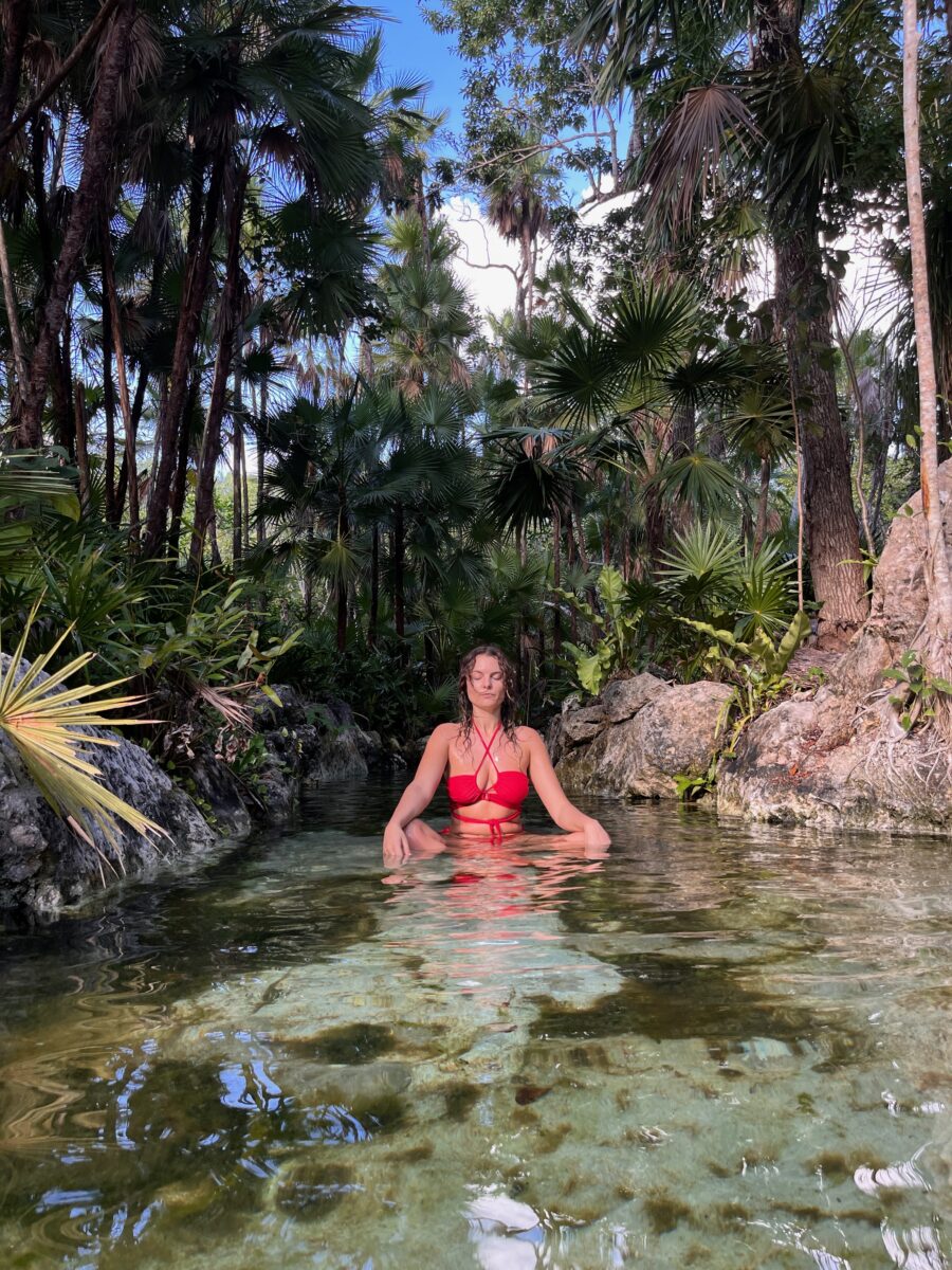 girl doing yoga meditation in a cenote in Tulum