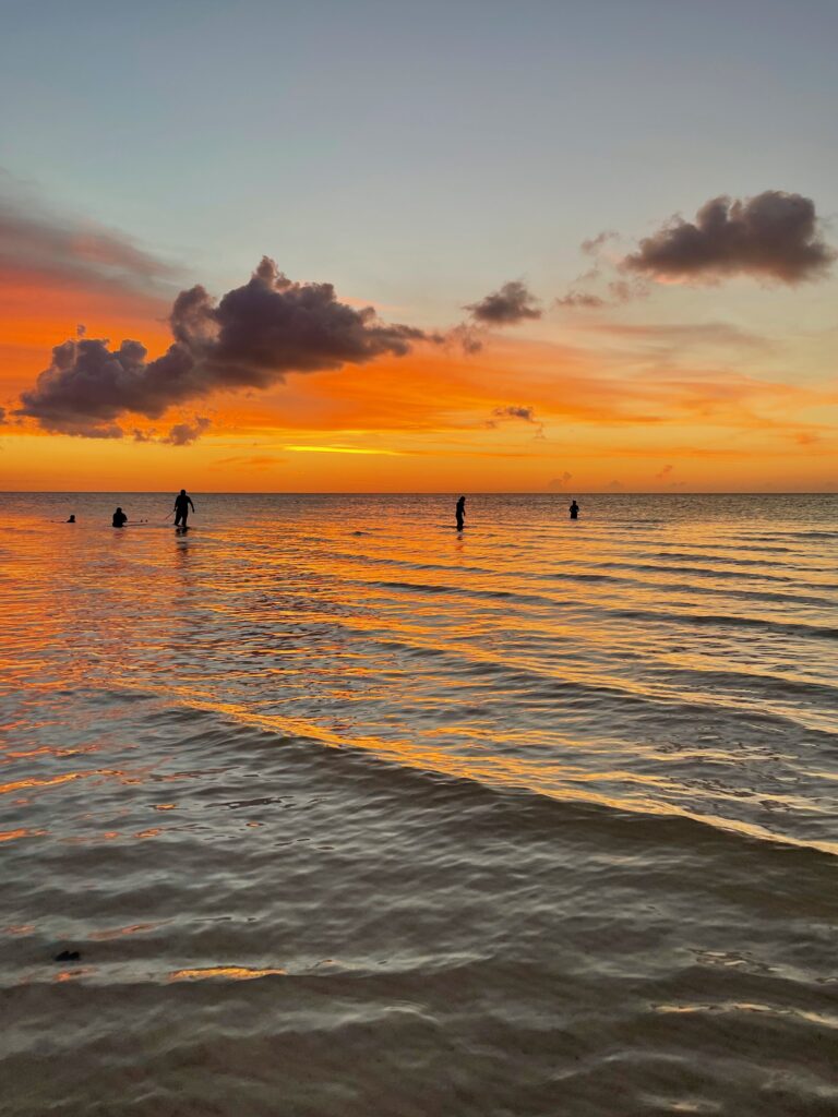 four fishermen in the shallow waters of Holbox beach with a vibrant sunset