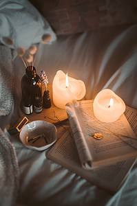 a journal, essential oils, and candles on a soft white bedding