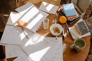 a desk covered in papers, books, and studying equipment