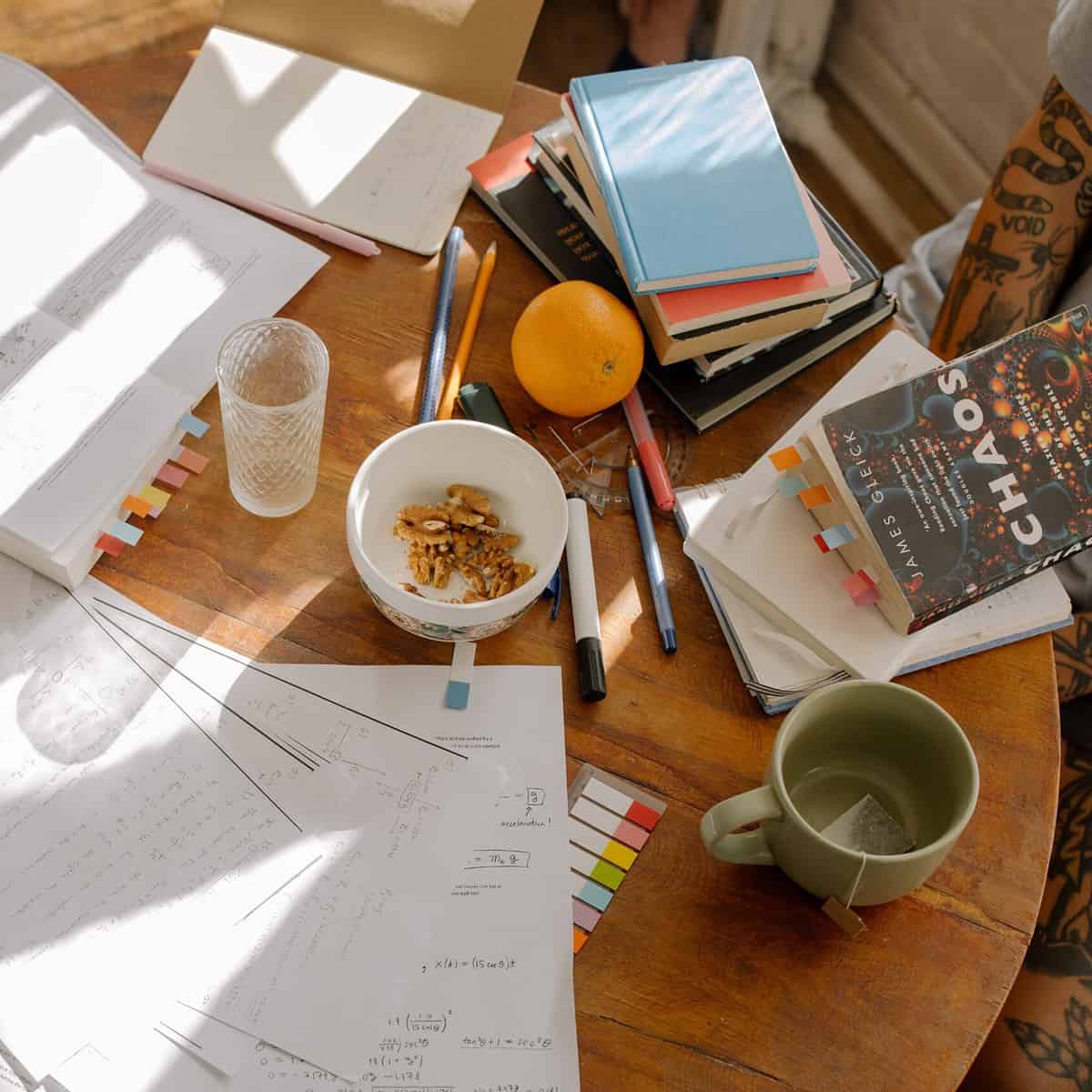 a desk covered in papers, books, and studying equipment