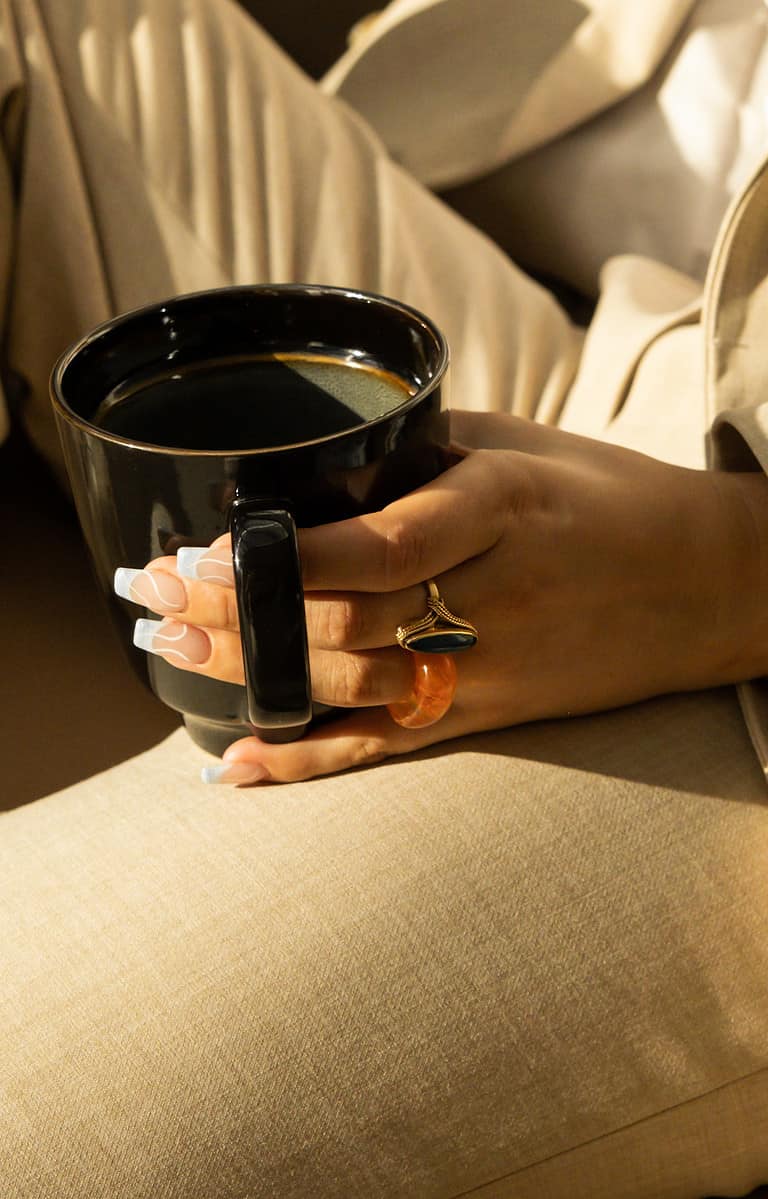 Sophie Pomme jewelry featuring a bold black ring and amber charm, styled on a hand with manicured nails, illustrating luxury accessories and elegant fashion details.