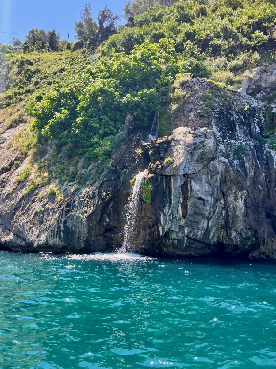 a cascade coming down on turquoise water sea on the Amalfi Coast