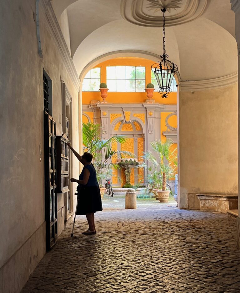 an elderly woman checking her mailbox in a picturesque and colourful alley of Rome