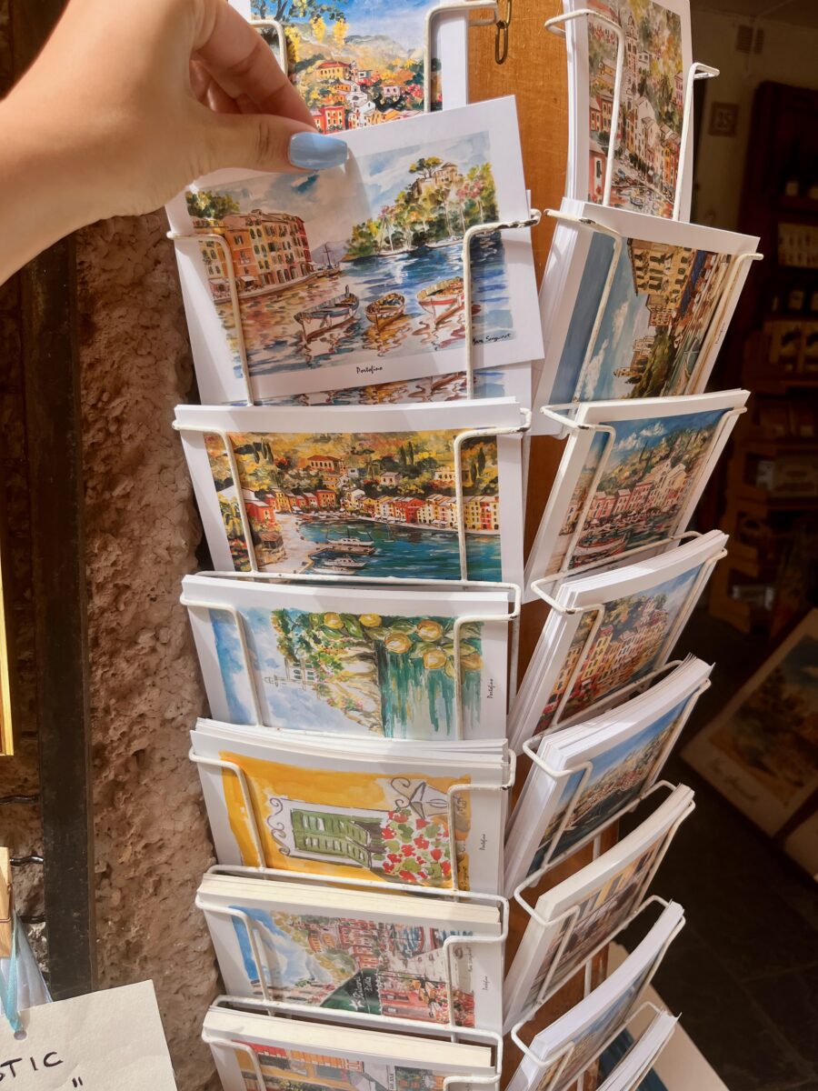 a hand searching for postcards of Portofino in Italy