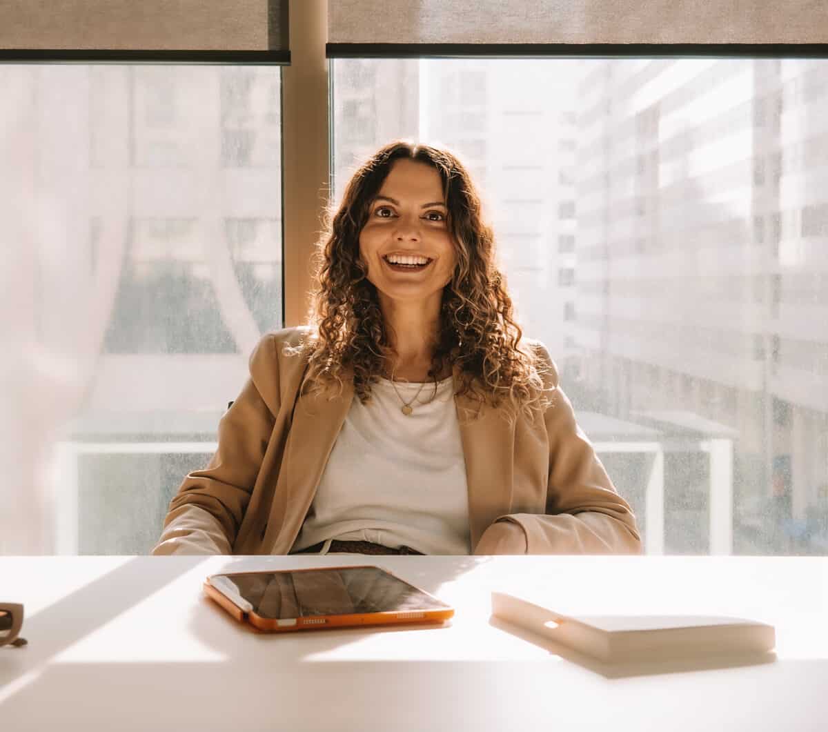 a smiling woman sitting behind a white desk