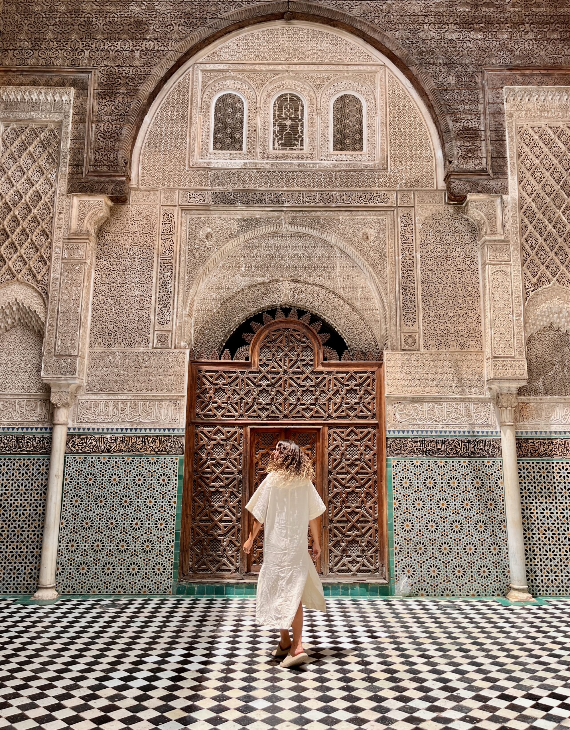 a woman twirling in a beautiful Moroccan architecture, Al Attarine Madrasa