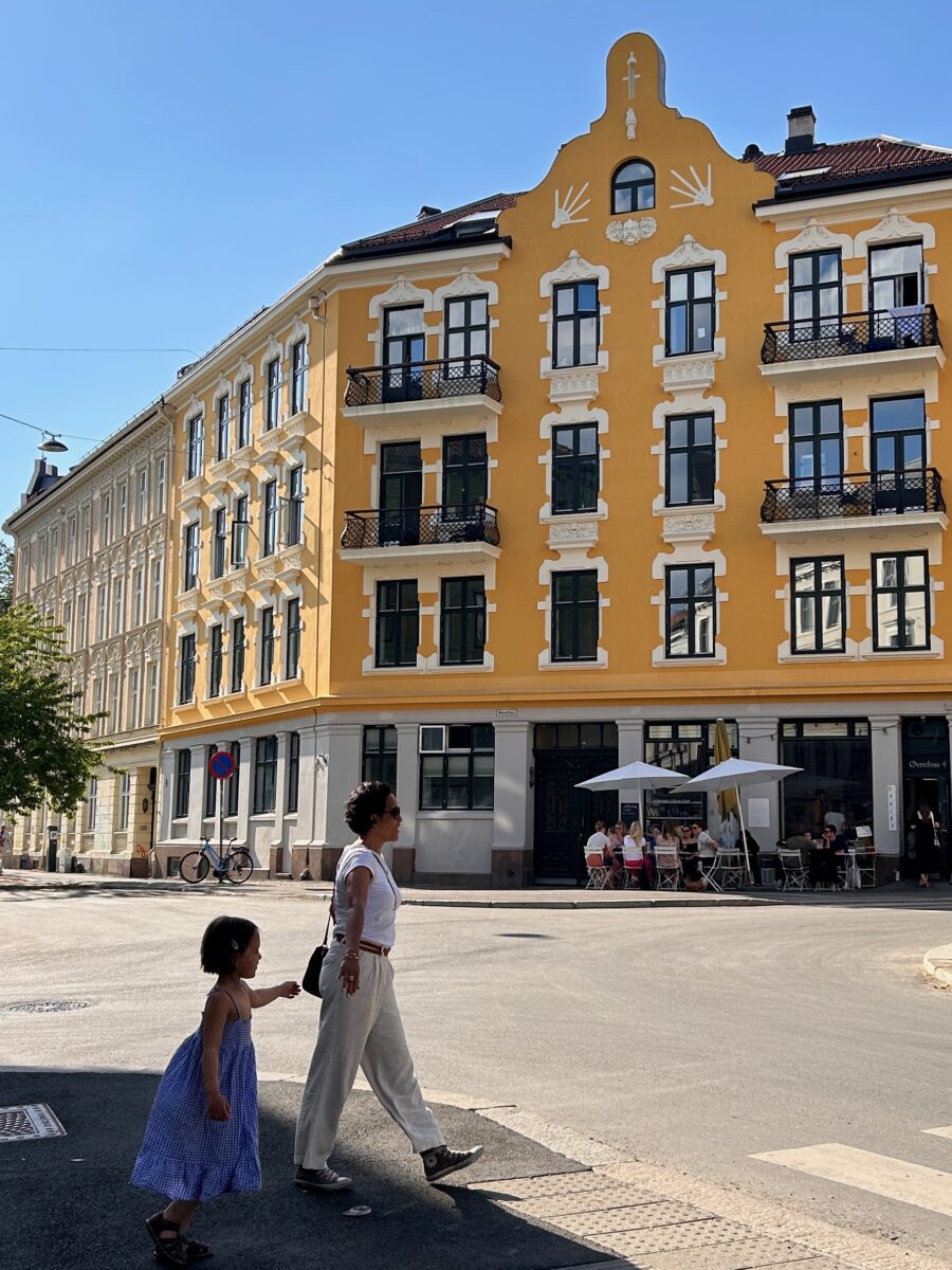 a woman and a child crossing a picturesque street of Oslo