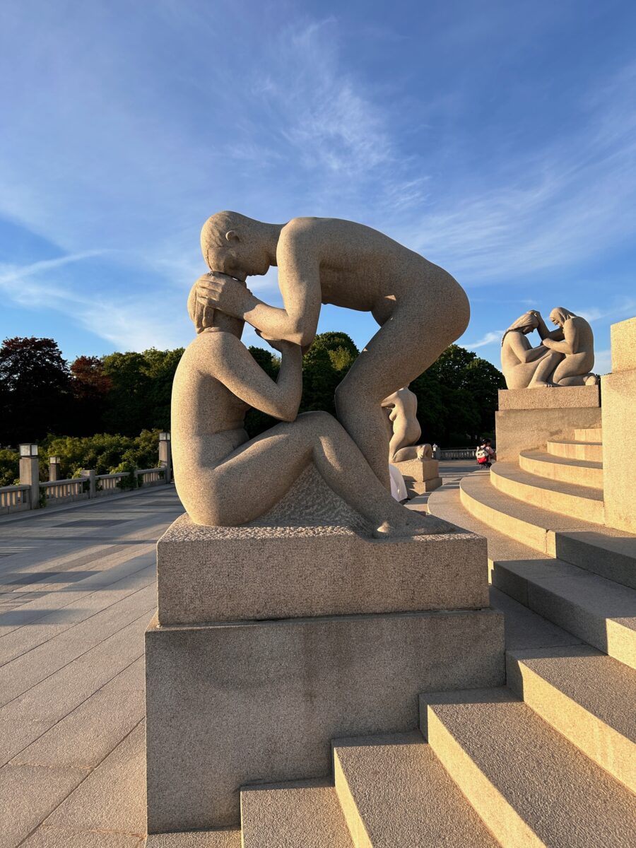 a sculpture of a woman kissing a seated man in the park of Oslo, Norway