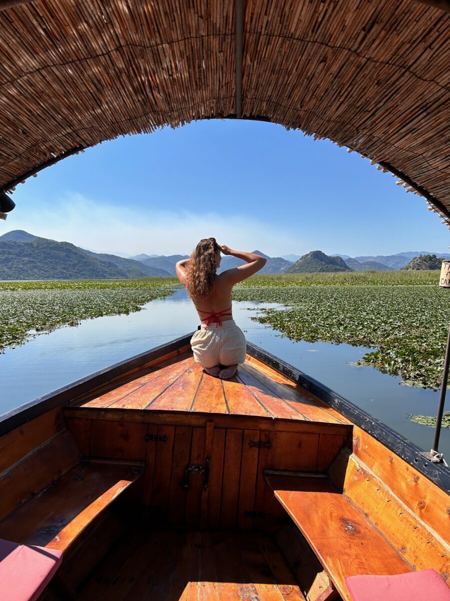 a woman on a boat overlooking the horizon on a lush lake in Albania