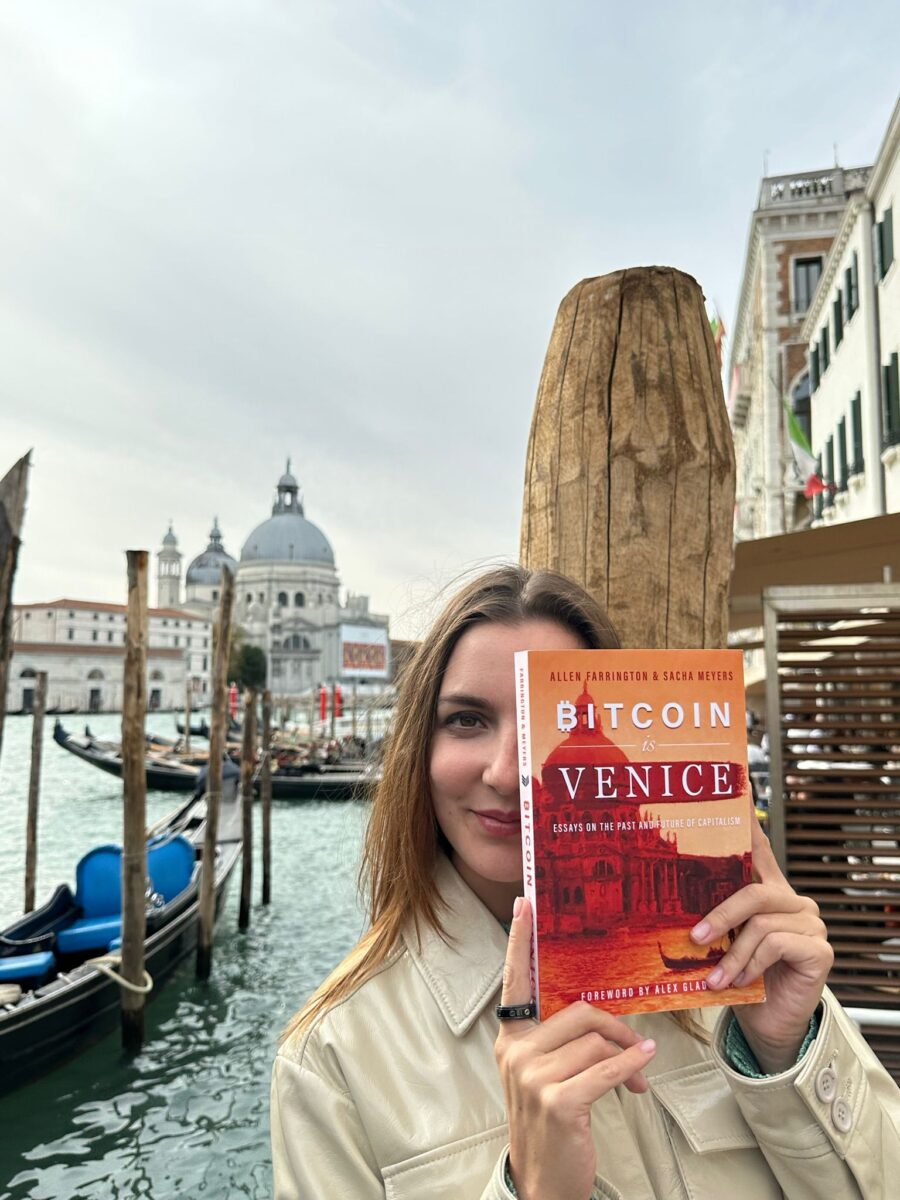 Ksenija Korolova holding a book about bitcoin in Venice