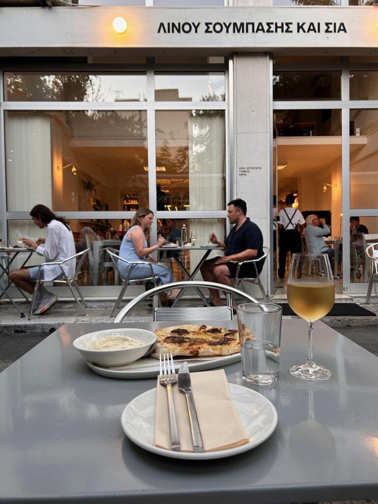 a restaurant table in Athens with traditional food and a glass of white wine