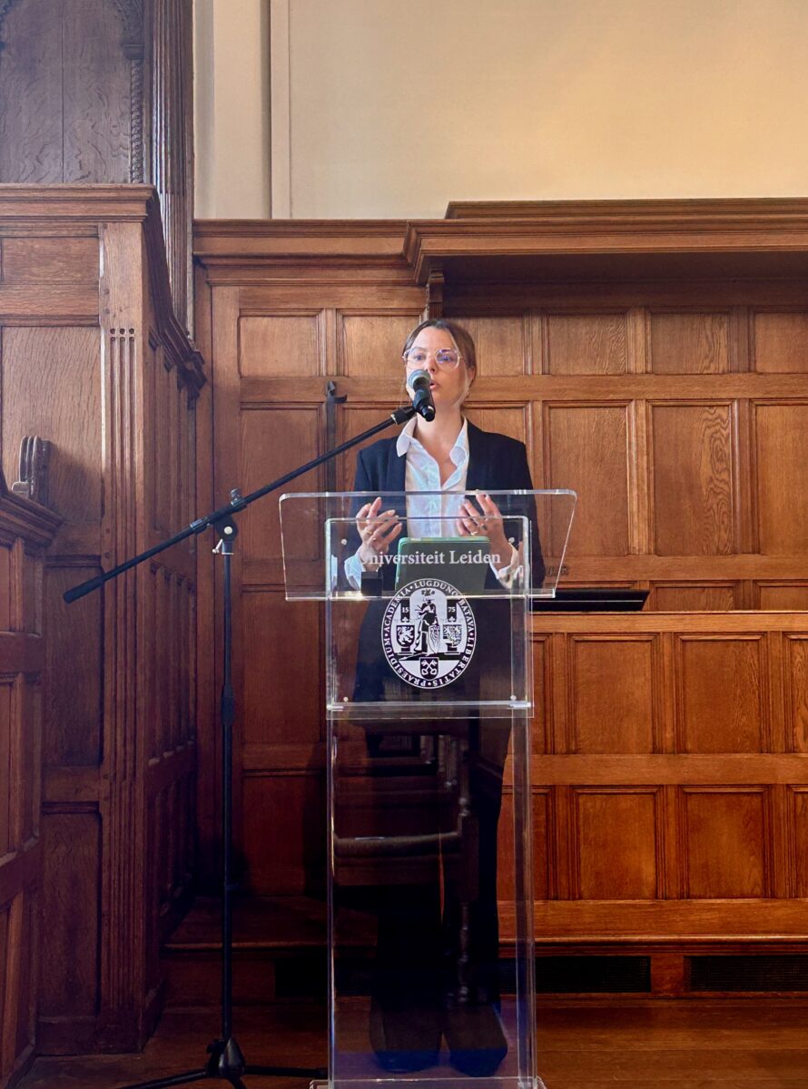 Sophie Veriter speaking at a podium with the seal of Leiden University
