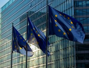 three flags of the European Union in front of the European Commission's building