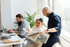 A Woman Sitting Between Men Pointing on a Paper at a large desk