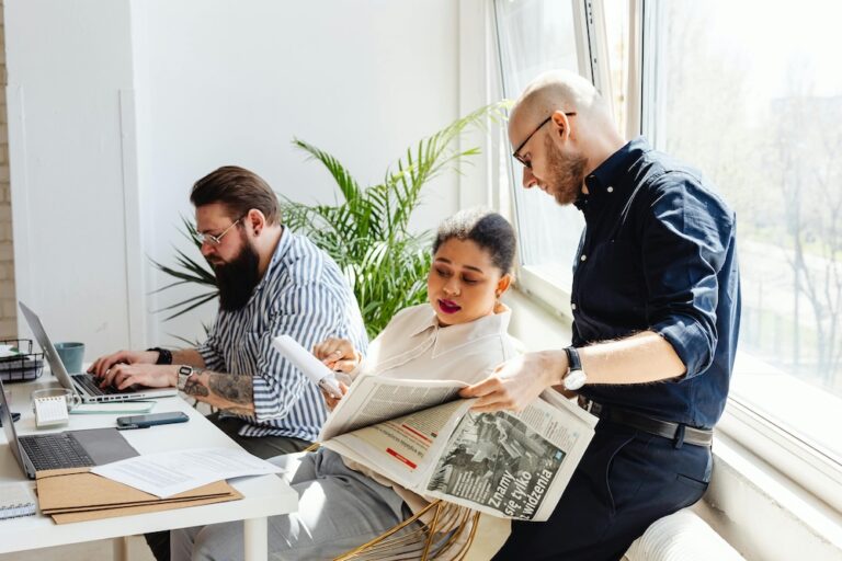 A Woman Sitting Between Men Pointing on a Paper at a large desk