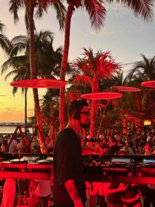 a DJ in front of a large audience, playing on a beach of Tulum, Mexico