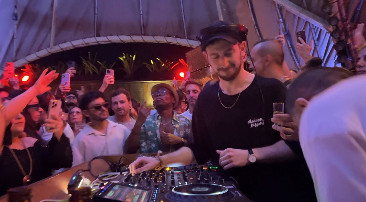 a beach club packed with people listening to a live DJ set